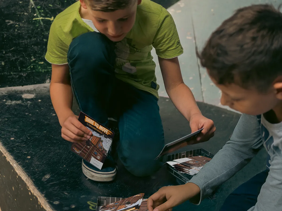 Twee leerlingen bekijken hun DAREcademy-challengeboekjes in het skatepark