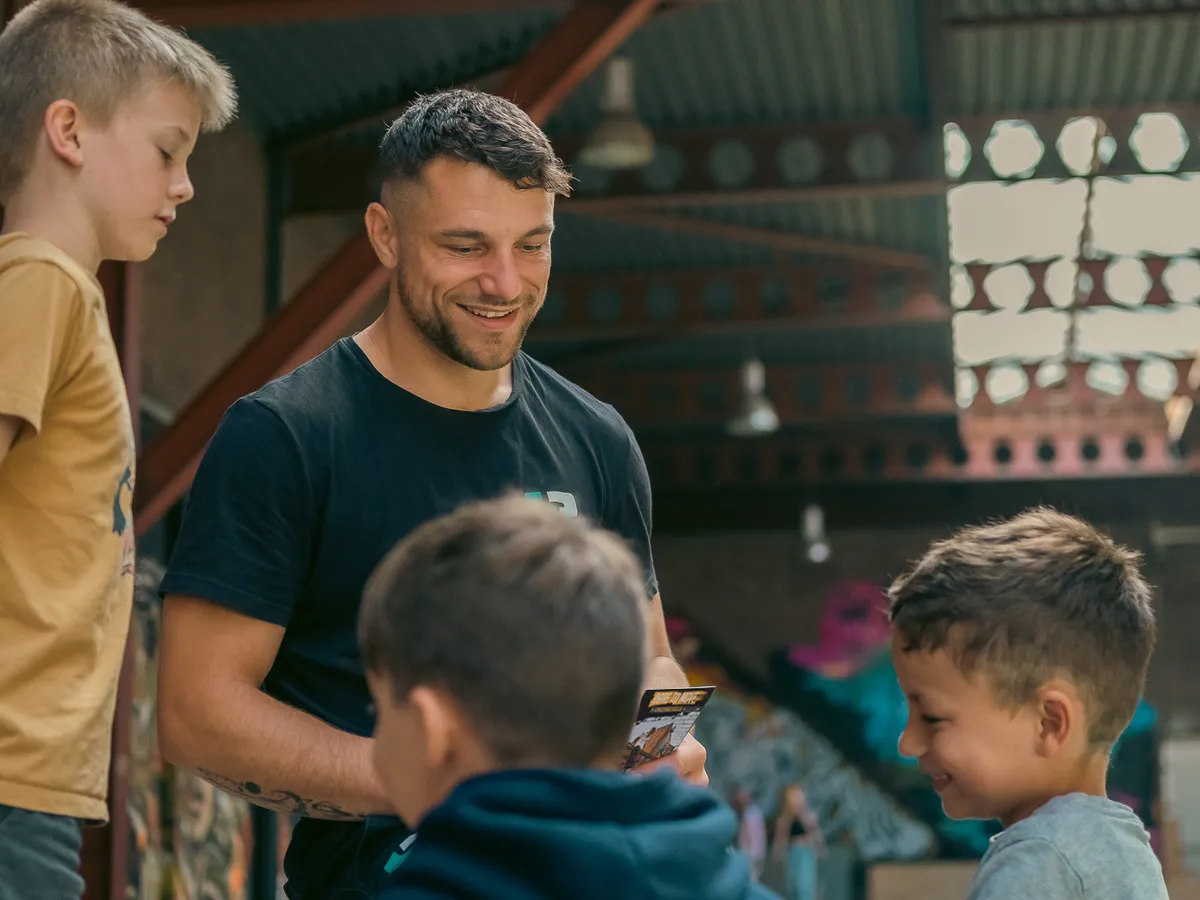 DAREcademy-coach bespreekt lachend het challengeboekje met een groepje leerlingen